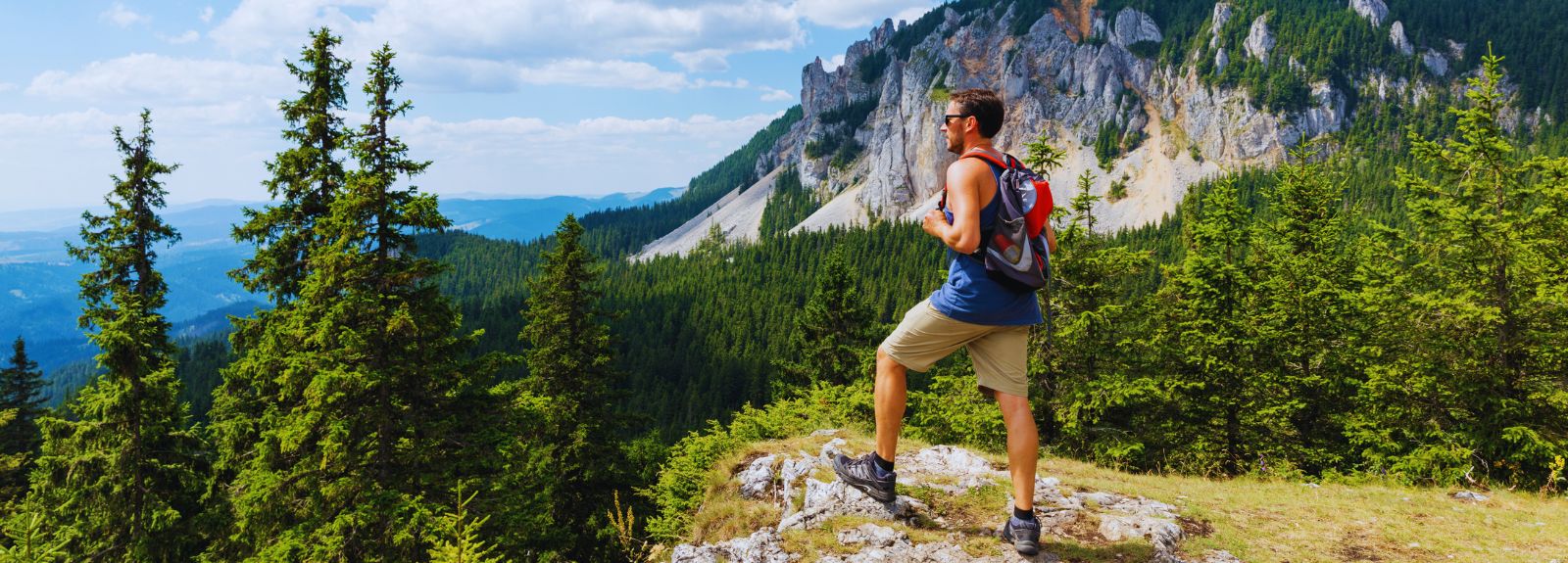 male standing at the top of a mountain looking at the view